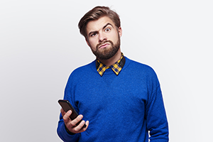 Young Man With Confused Face and Phone In Hand